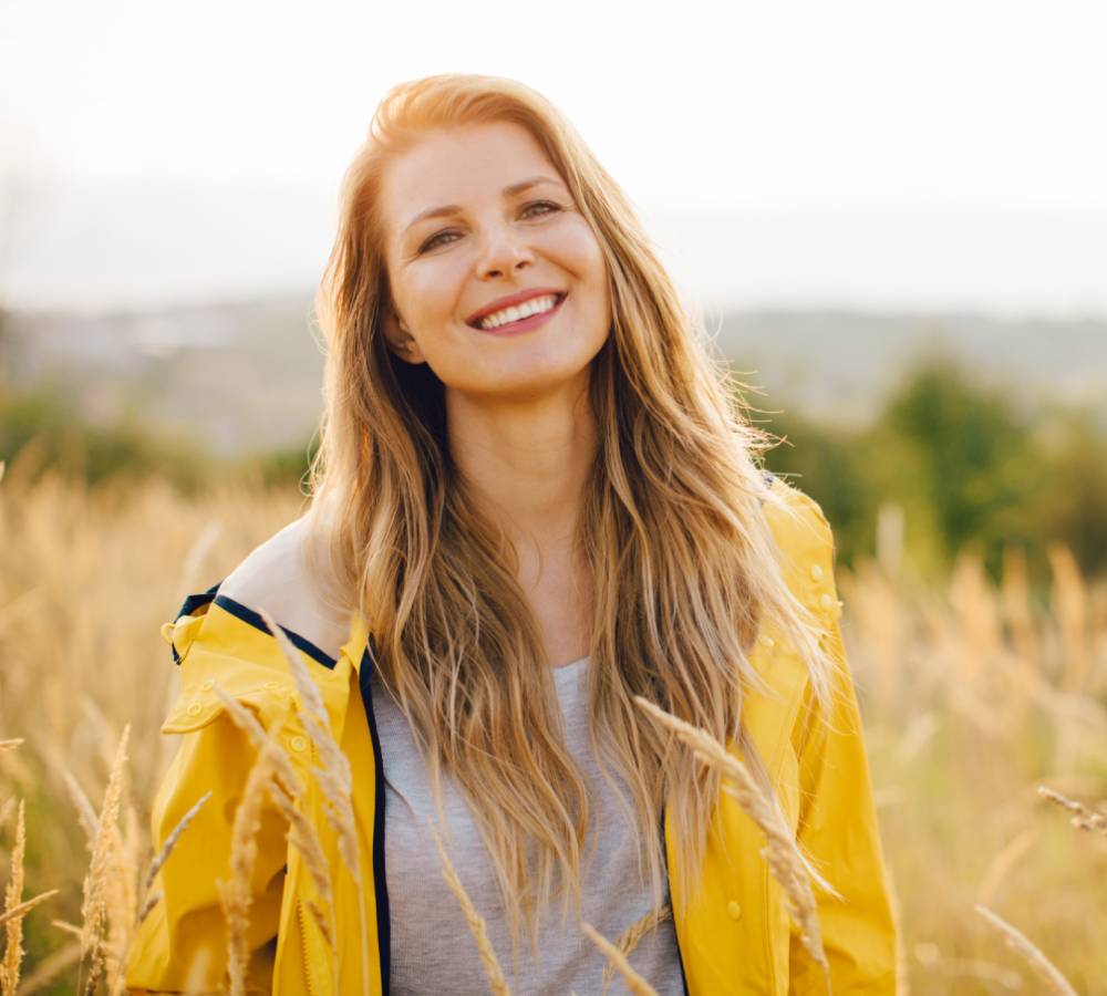 Woman smiles in a field.